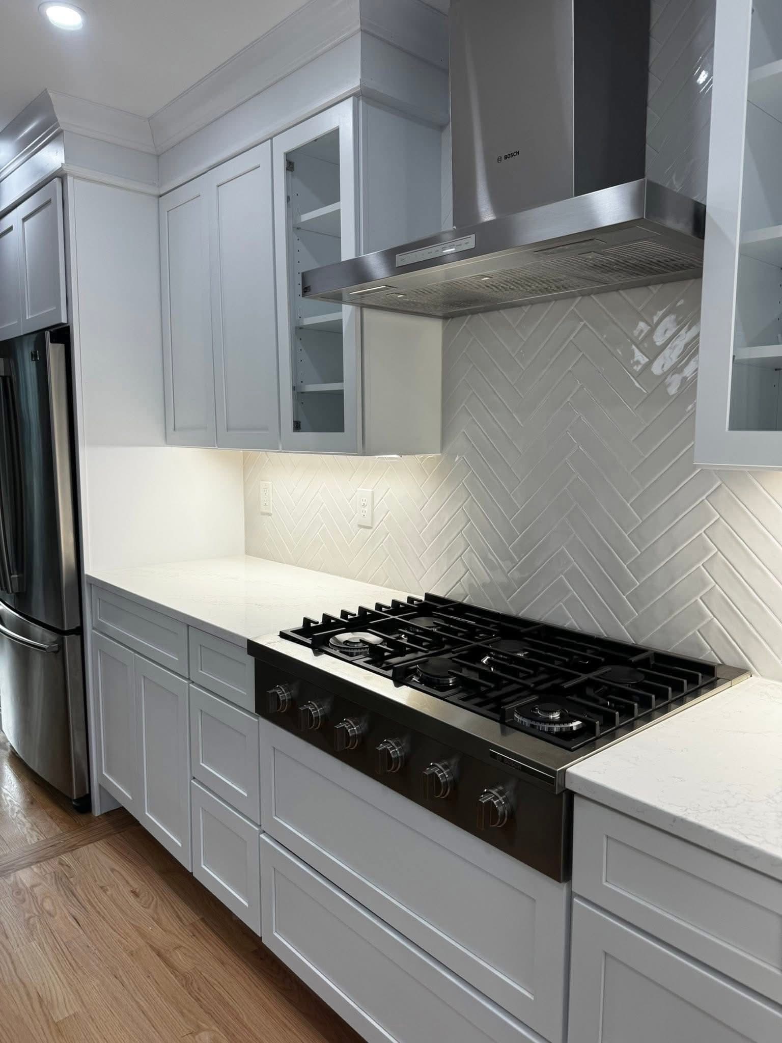 Herringbone tile backsplash with range hood detail
